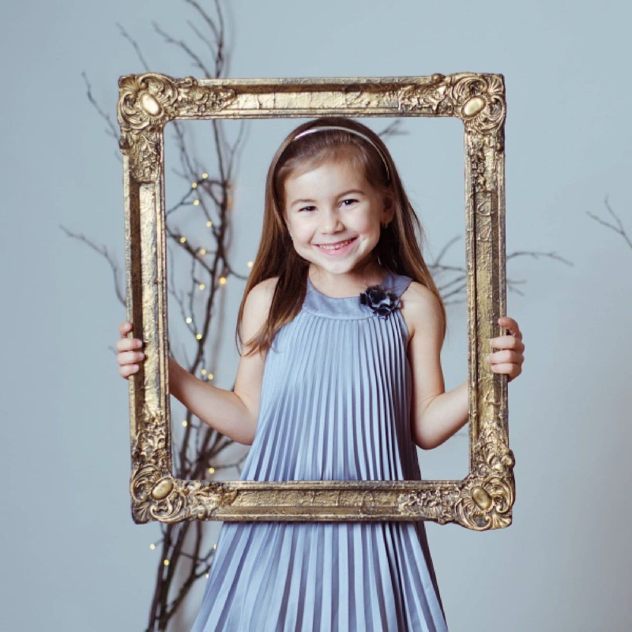 A smiling girl holding a golden picture frame