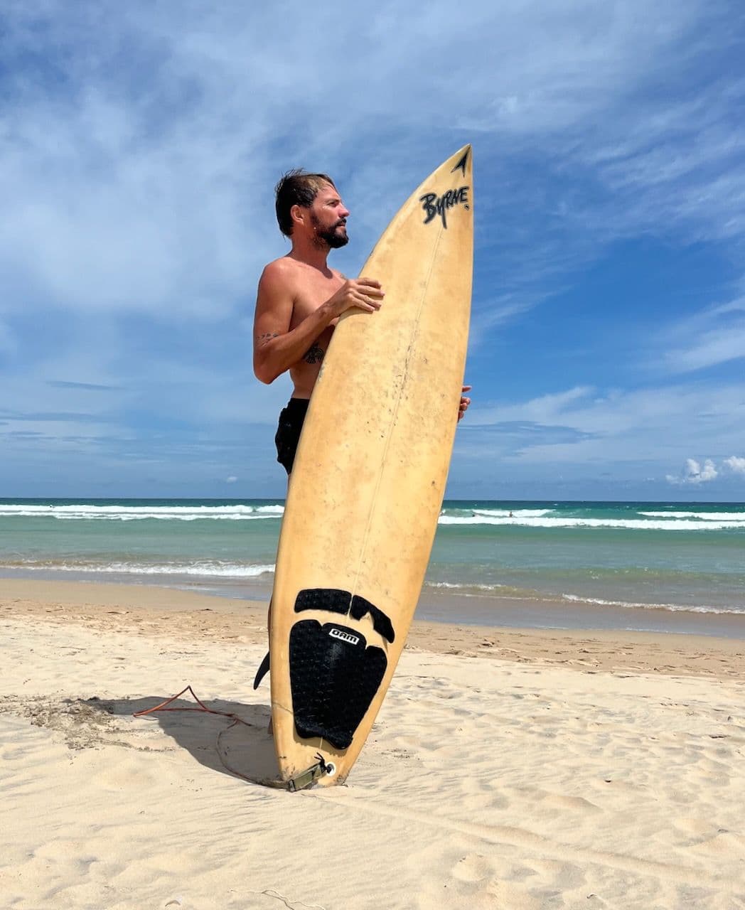 With a surfboard on the beach